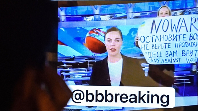 A man looks at a computer screen watching a dissenting Russian Channel One employee, Marina Ovsyannikova who enters an on-air TV studio during Russia's most-watched evening news broadcast on 14 March