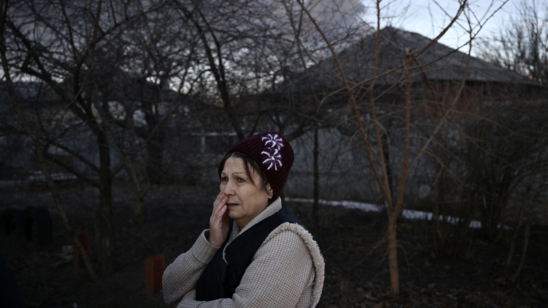 A woman stands in a street as black smoke rises from a military airport near Kharkiv on 24 February,
the first day of Russia's invasion of Ukraine