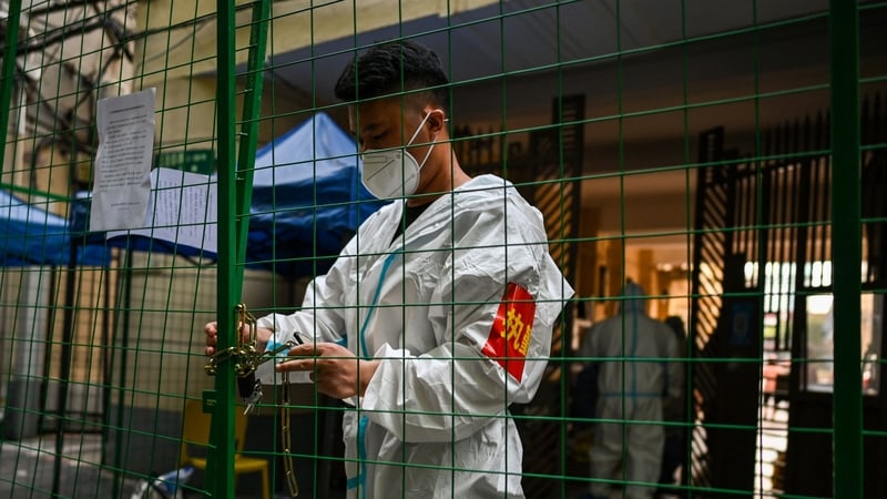 A worker padlocks fencing securing a residential area under Covid-19 lockdown in the Xuhui district of Shanghai