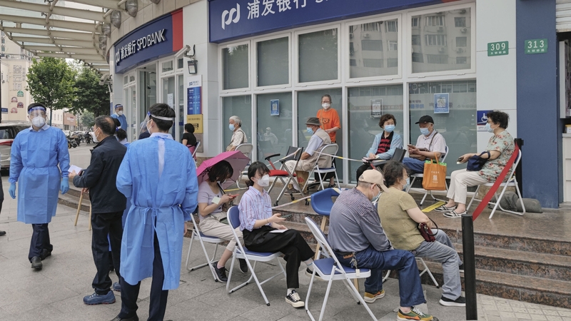 Customers queue in front of a branch of Shanghai Pudong Development Bank in Shanghai