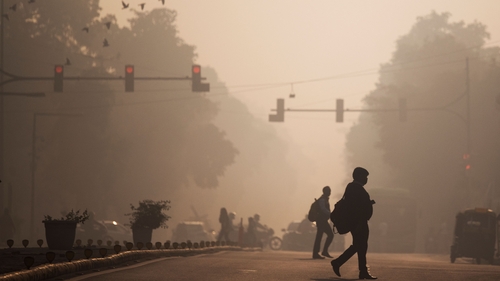 Commuters cross a street amid smoggy conditions in New Delhi. India exceeds WHO guidelines on air pollution ten-fold (file image)