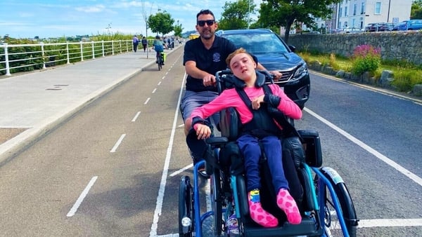 Sophia with her dad Aaron on the new wheelchair tricycle