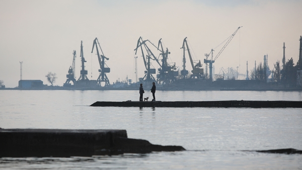 A couple walks a dog on a pier by the Sea of Azov in Ukraine's industrial port city of Mariupol