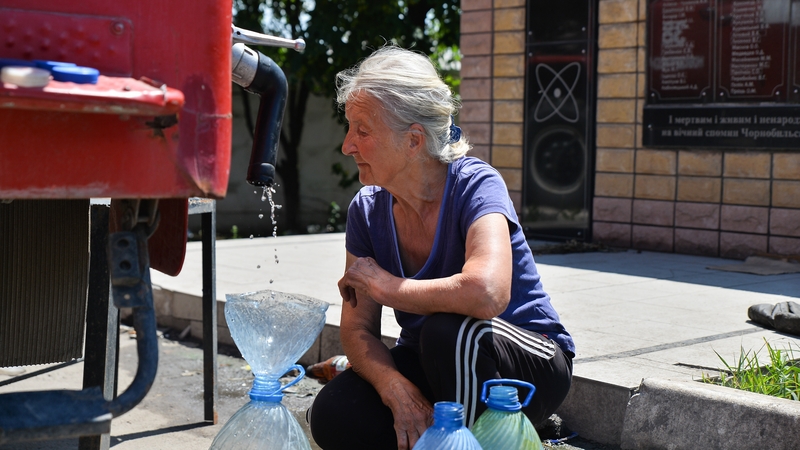 Bean ag líonadh buidéil uisce i Lysychansk, 19 Meitheamh 2022