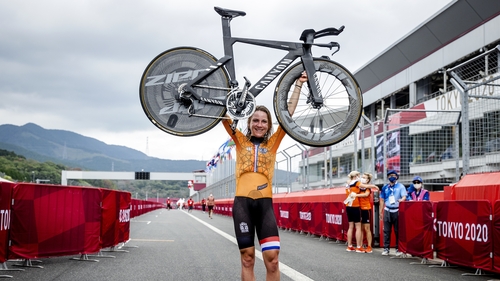 Van Vleuten holds her bike above her head after winning the individual road time trial at Tokyo 2020