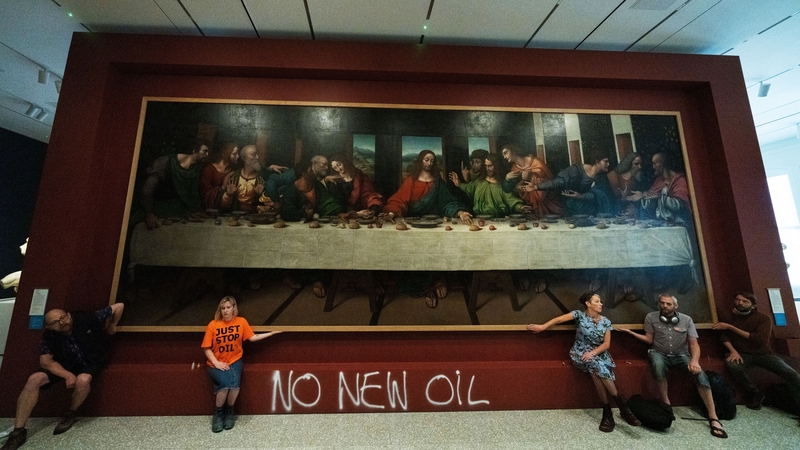 Activists sprayed paint on the wall and glued themselves to the frame of a copy of The Last Supper