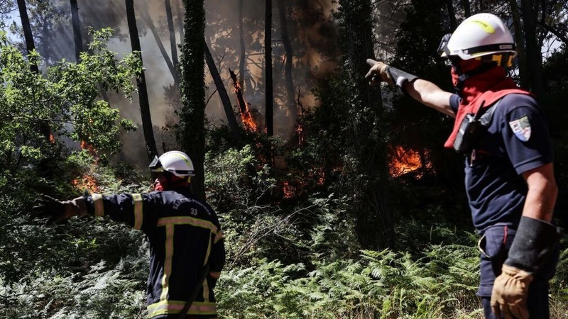 Firefighters work to extinguish a wildfire which broke out at the bottom of the Dune du Pilat, southwestern France
