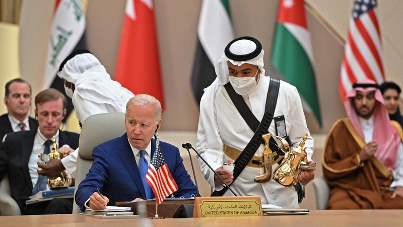US President Joe Biden takes notes while an usher serves coffee during the Jeddah Security and Development Summit in Saudi Arabia