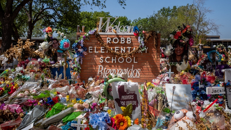 The Robb Elementary School sign is seen covered in flowers and gifts this morning