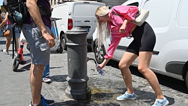 A girl fills a bottle with water from a fontain in central Rome