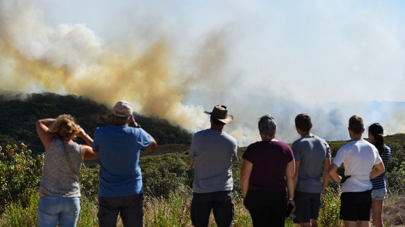 People watch a forest fire near Gignac, southern France, as the country endures one of its driest summers on record