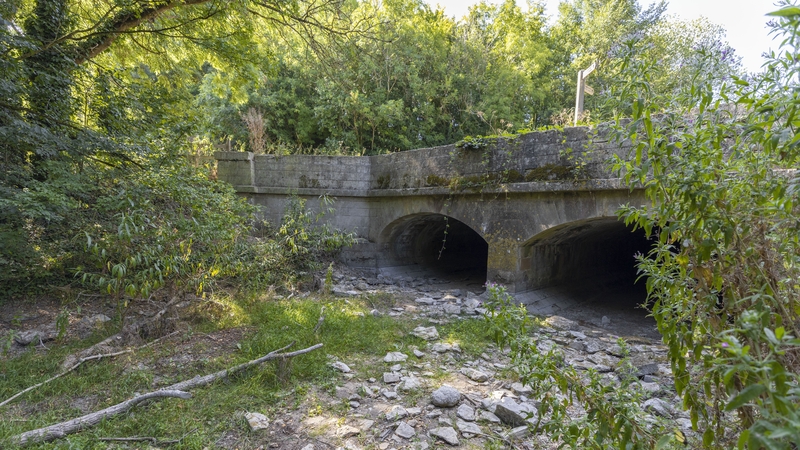 A bridge crosses the dried bed of the River Thames near the river's source at Thames Head