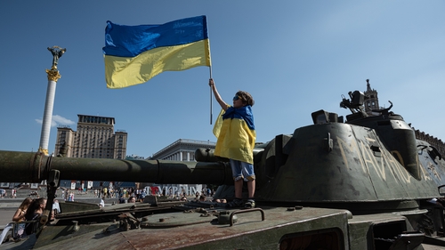 A boy stands on top of a Russian military vehicle displayed in Kyiv