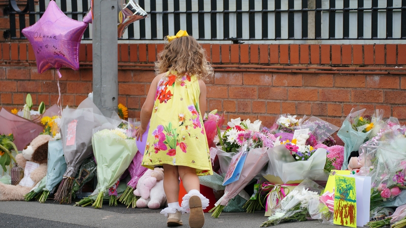 A young girl lays a tribute in Kingsheath Avenue, Liverpool, where nine-year-old Olivia Pratt-Korbel was fatally shot