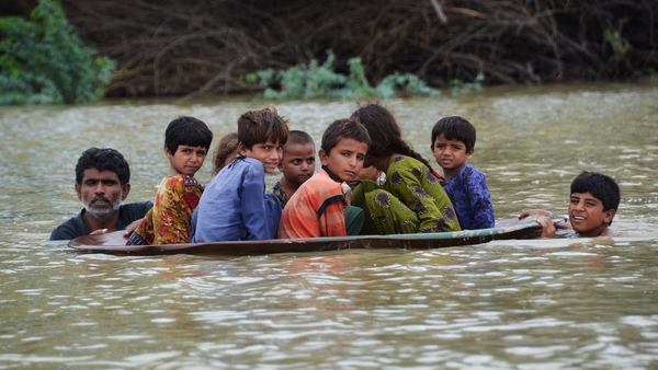 A man uses a satellite dish to move children across a flooded area in Jaffarabad district