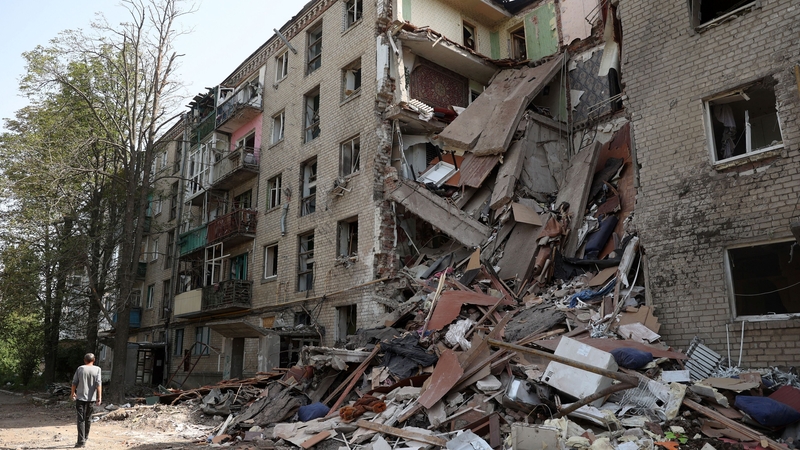 A man walks past a heavily damaged residential building in the town of Bakhmut today
