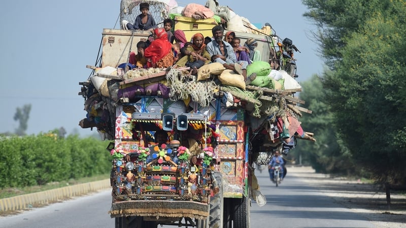 Displaced people sit on a tractor with their belongings after fleeing from their flood-hit homes in Shikarpur of Sindh province