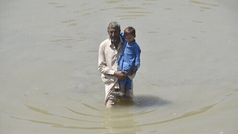 A man with a child in Pakistan's northwest Charsadda district, as the UN warns of 'many more child deaths'