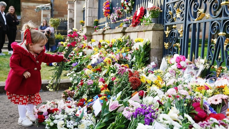 Abigail Glen, 2, from Lisburn, lays flowers at the gates of Hillsborough Castle, Co Down