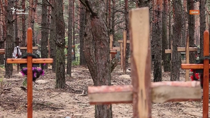 Grianghraf de choill in Izium, ina bhfuil criosanna adhmaid atá déanta go simplí ar fud na háite.