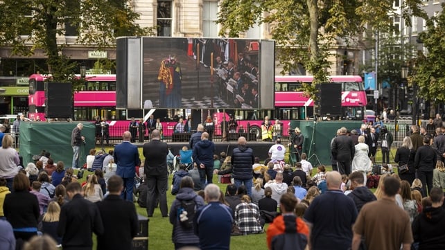 People in the grounds of Belfast City Hall watch the funeral on a large screen today (Liam McBurney/PA)