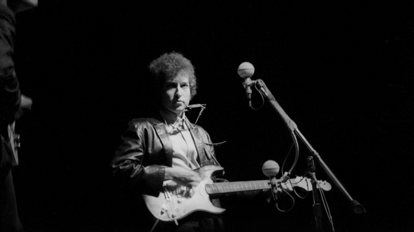 Bob Dylan plays a Fender Stratocaster electric guitar for the first time on stage as he performs at the Newport Folk Festival on July 25, 1965 in Newport, Rhode Island. July, 1965. (Photo by Alice Ochs/Michael Ochs Archives/Getty Images)