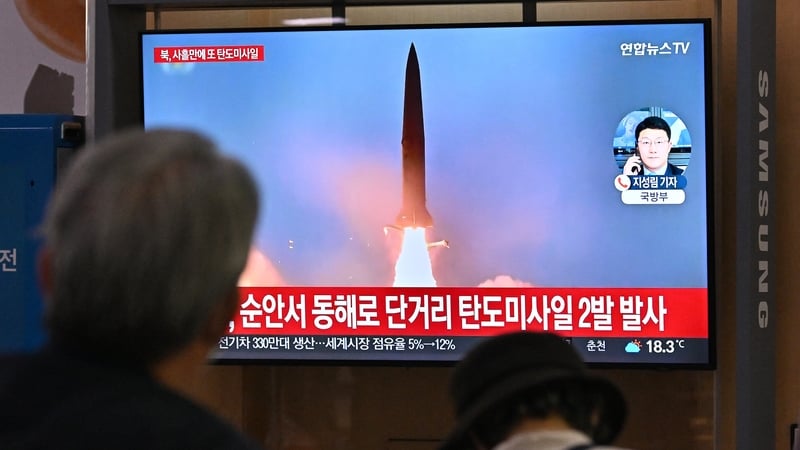 People watch a television screen showing a news broadcast with file footage of a North Korean missile test