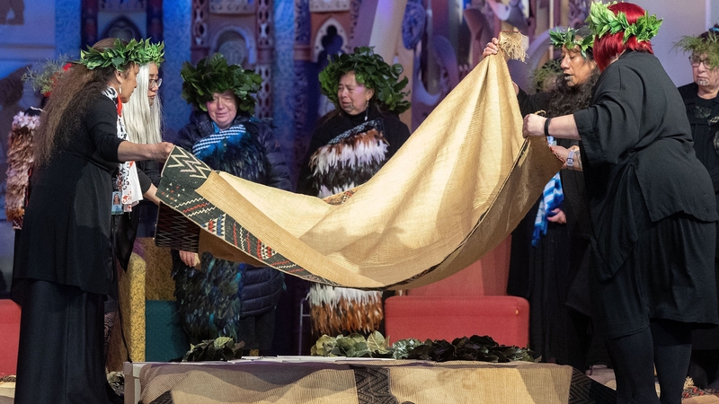 Descendants place cloaks over boxes with the ancestral remains of Maori and Moriori that were returned from the Natural History Museum Vienna during a welcoming ceremony at Te Papa