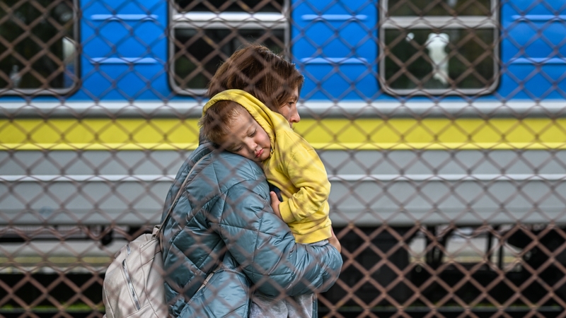 A Ukrainian woman carries her child as they get off a train from Zaporizhzhia at Przemysl train station in Poland