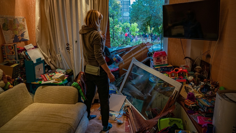 A woman looks out the broken window of a damaged apartment following a Russian missile strike on Dnipro in Ukraine. Photo: AFP