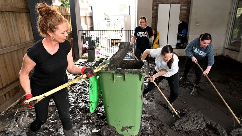 People clear mud from a property damaged by floods in the Melbourne suburb of Maribyrnong