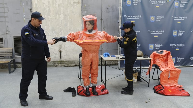 Ukrainian Emergency Ministry rescuers assist a woman to put on protective clothing during a nuclear emergency training session for civilians in Kyiv last month. Photo: Mykola Tys/SOPA Images/LightRocket via Getty Images