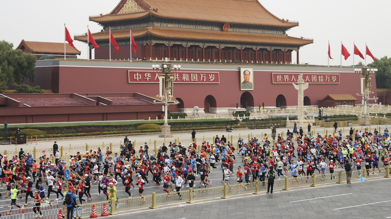 Participants run past the Tiananmen Gate during the marathon