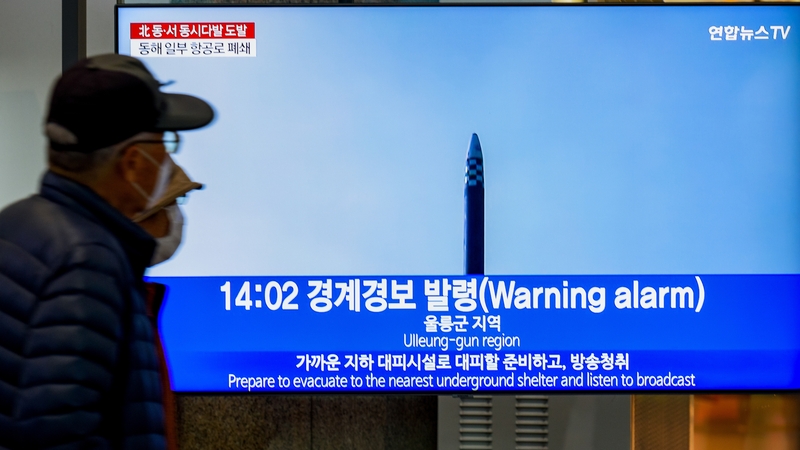 People watch a news broadcast flashing a warning alarm after a North Korean missile launch on 2 November