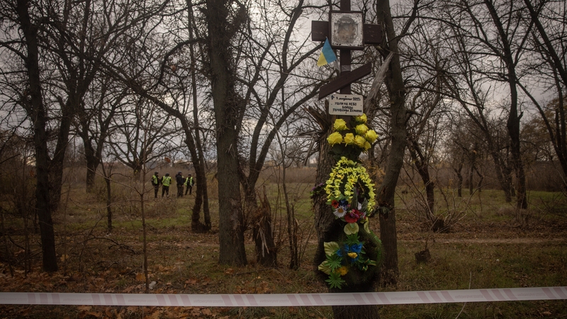 Police investigators search and record evidence in a city park in Kherson
