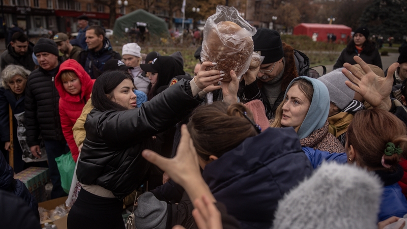 People crowd around volunteers to receive food aid in Kherson's central square