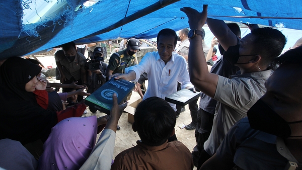 Indonesian President Joko Widodo provides aid to people at a temporary shelter