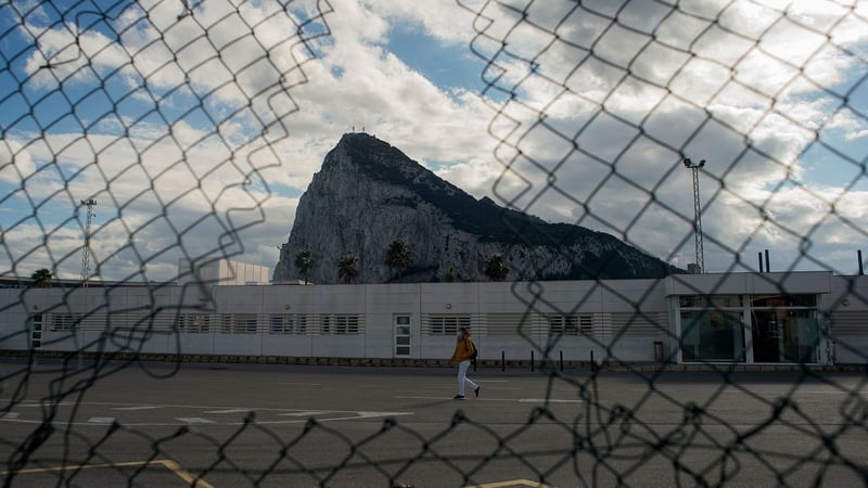 A woman walks past the Rock of Gibraltar as she crosses the border between Spain and Gibraltar in La Línea de la Concepción