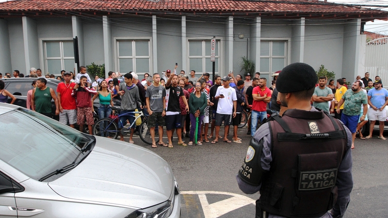Locals gather outside the police station where the perpetrator of two school shootings was held in Aracruz, Brazil