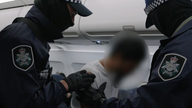 Australia police escort Neil Christopher Prakash from a plane (Courtesy:Australian Federal Police)