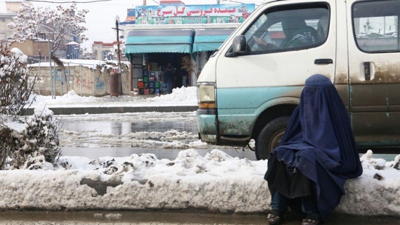 A woman sits snowy road after snowfall in Kabul, Afghanistan