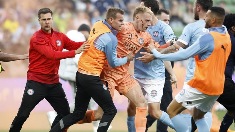 A bleeding Tom Glover of Melbourne City is escorted from the pitch by team mates