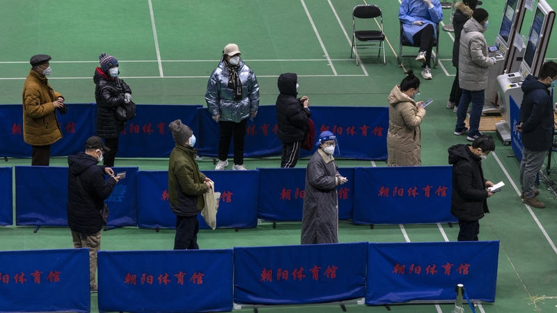 People wait to see a health worker at a temporary fever clinic in a sports centre in Beijing