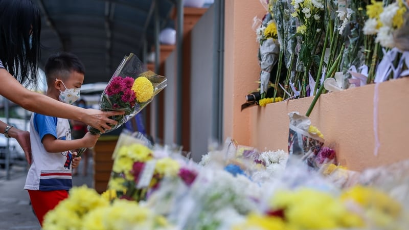 Students and parents place flowers and condolence messages at the entrance of Mun Choong school as a tribute to the victims of the Batang Kali landslide