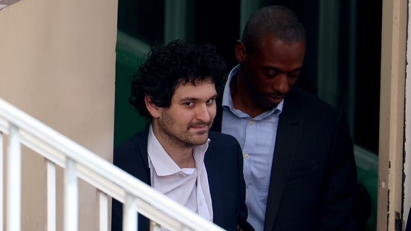 FTX co-founder Sam Bankman-Fried is escorted out of the Magistrate's Court in Nassau, Bahamas