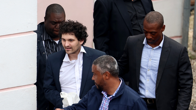 FTX co-founder Sam Bankman-Fried is escorted out of the Magistrate's Court in Nassau, Bahamas, yesterday