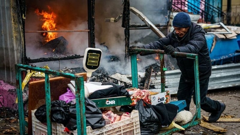 A man pushes a cart in front of a burning shop after Russian shelling to Ukrainian city of Kherson on Christmas Eve