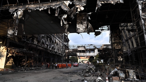 A rescue team walks through a burned out part of the Grand Diamond City hotel-casino after a major fire