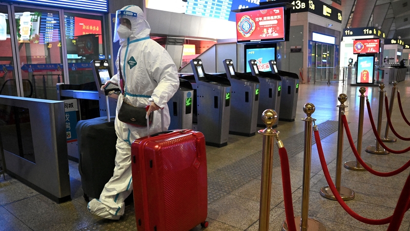 A passenger wearing personal protective equipment to halt the spread of Covid-19 arrives at a train station in Beijing