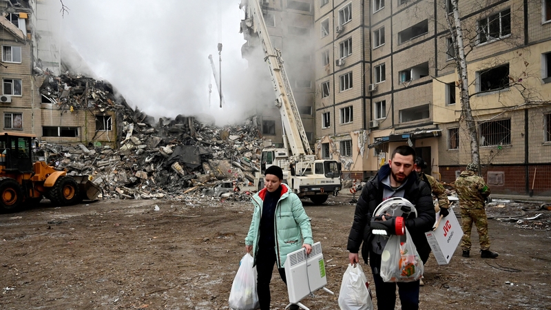 Residents carry their belongings from a residential building destroyed after a missile strike in Dnipro